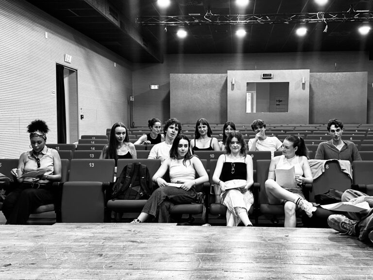 DRAMA students sitting in the stalls of a theatre, in black and white, in front of the stage