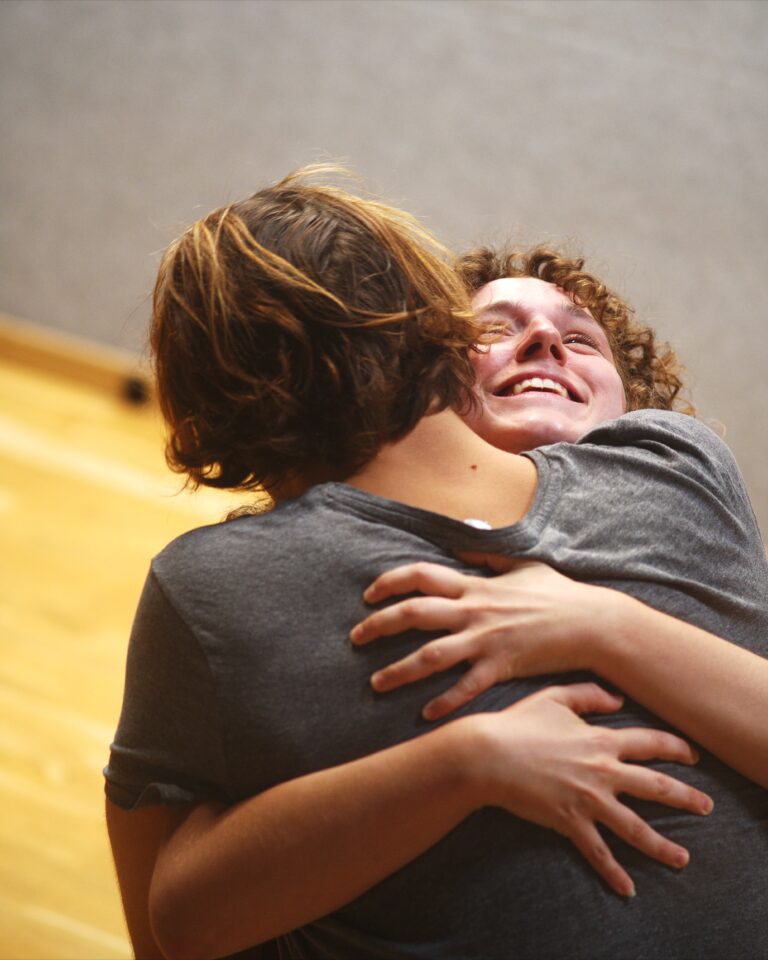 Two students hug laughing during the DRAMA Open Day