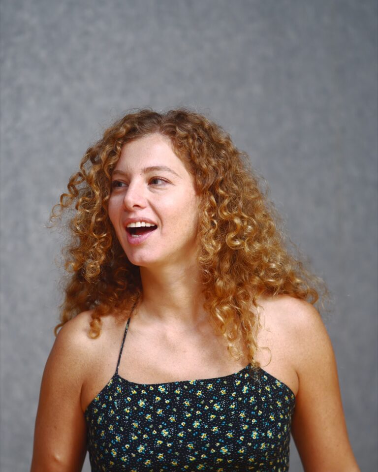 A curly-haired student laughs during the DRAMA Open Day
