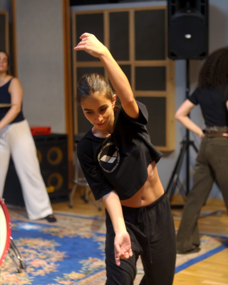 A student in motion with her arm raised during an exercise in the studio