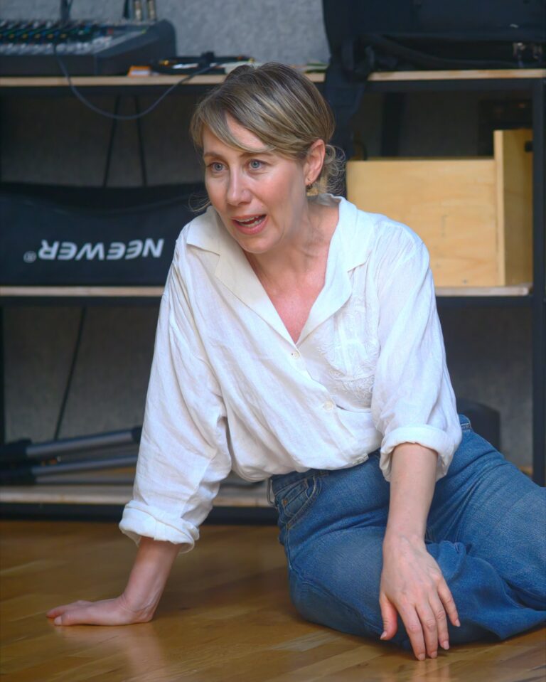 A student sitting on the floor speaks to the group during the DRAMA Open Day
