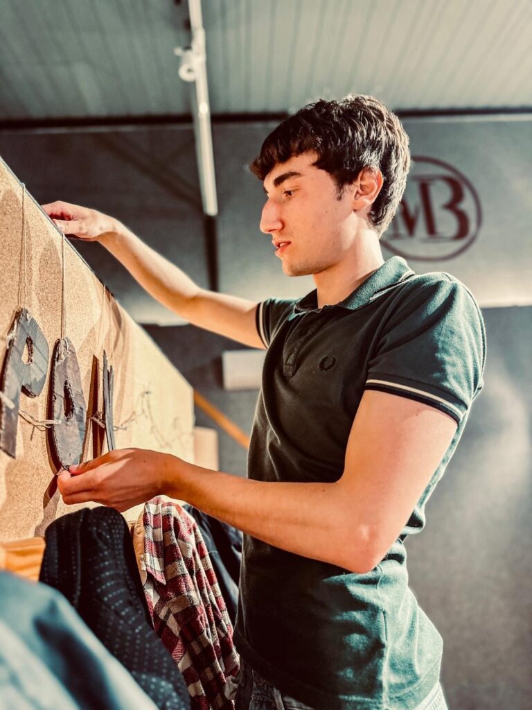 A student hangs the cardboard letters of the Almost Maine sign