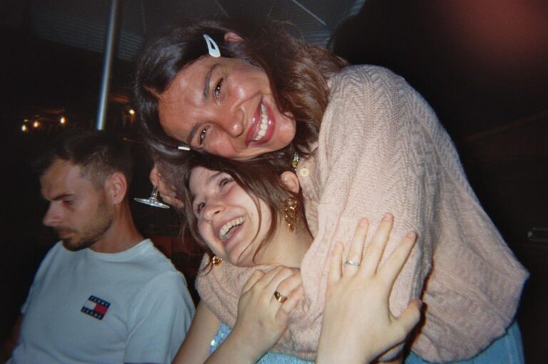 Two students hug laughing at the table