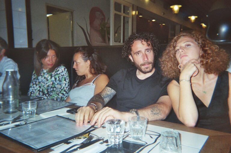 Four students at a pizzeria table, in an analogue photo