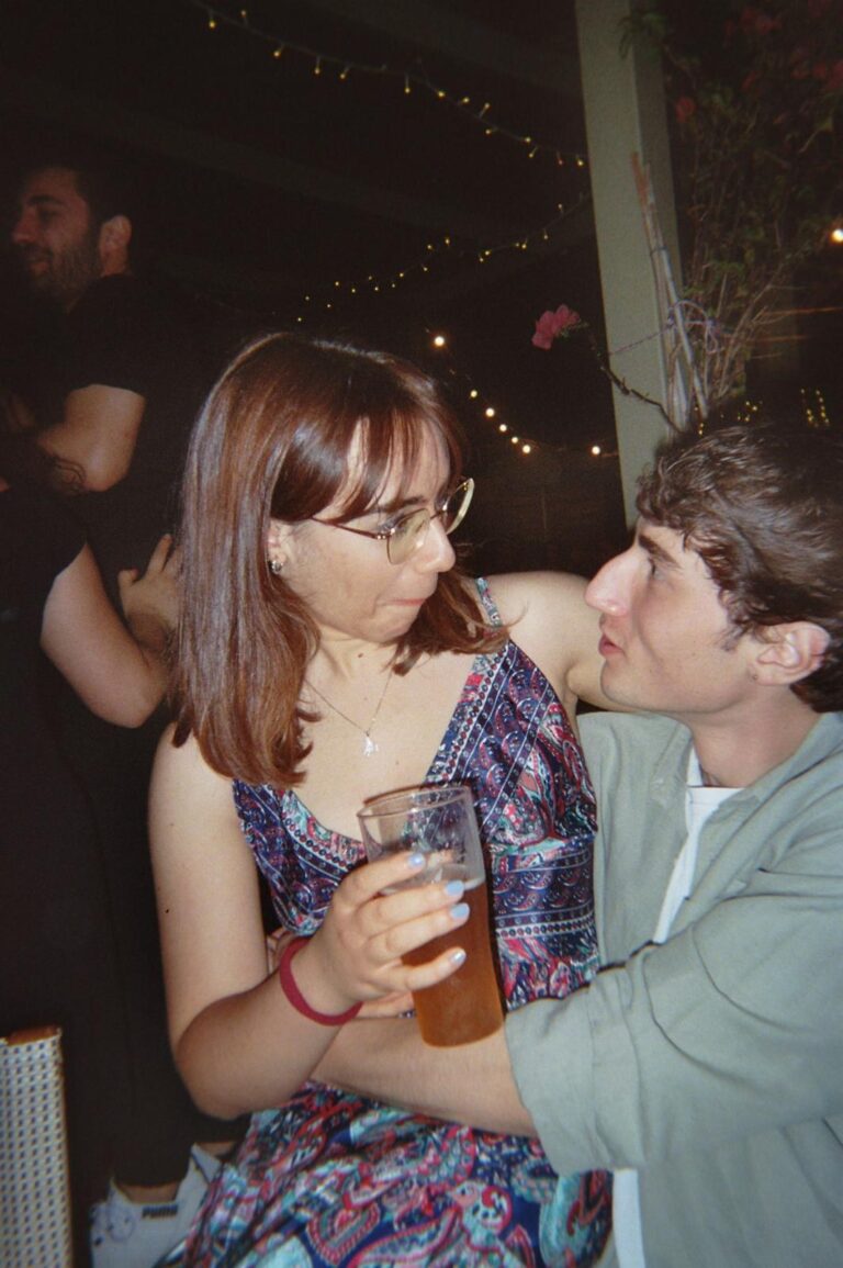 Two students look at each other at dinner, beer in hand