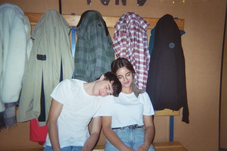 Two students leaning on each other on the coat-rack bench