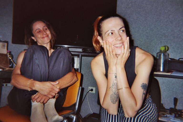 Two students laughing, seated in the studio