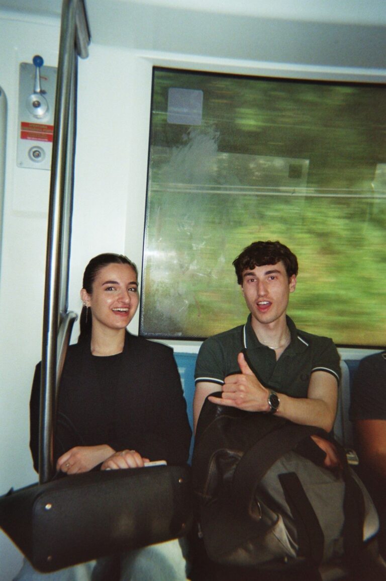 Two students on the metro, one makes the shaka sign