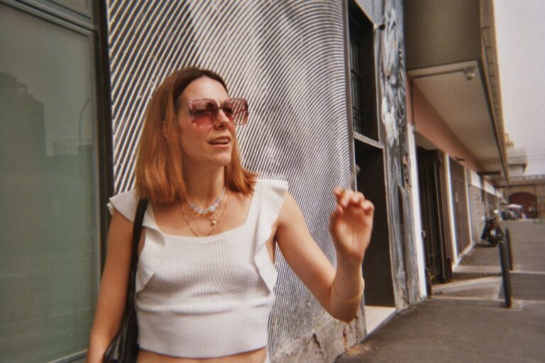 Portrait of a woman with pink glasses in front of a mural