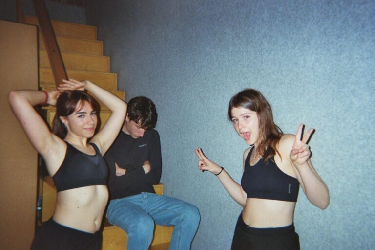 Three students in the studio, near the wooden staircase, posing