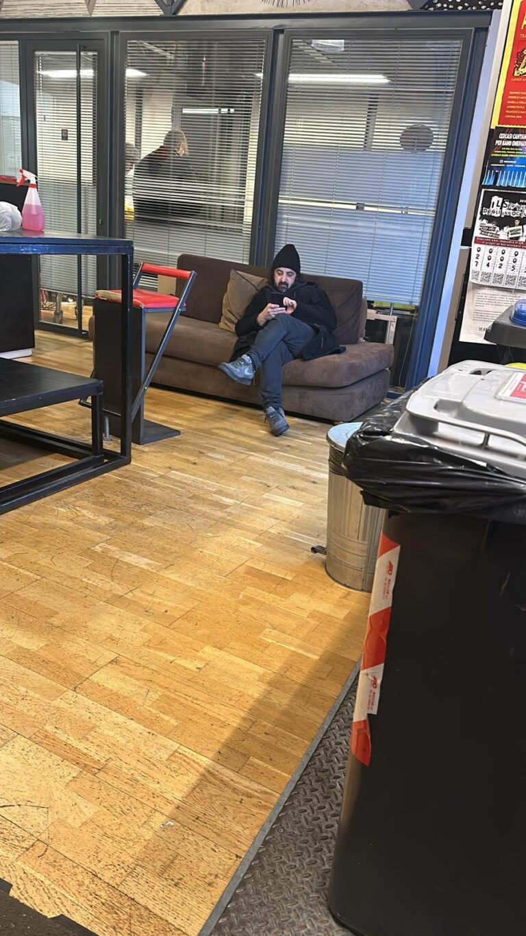 A student in a hat on the entrance sofa, phone in hand