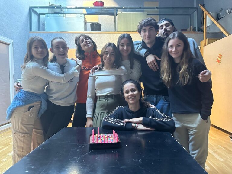 Students in the studio around a black table with the birthday cake