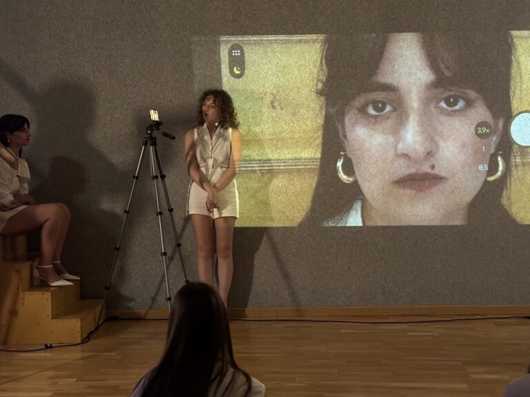 Persona: performer accanto al volto proiettato
