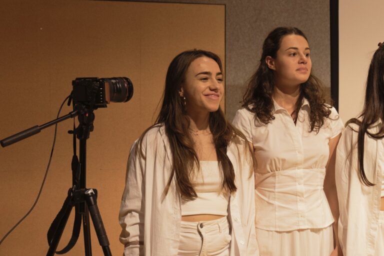 Persona: Due performer sorridenti accanto alla camera