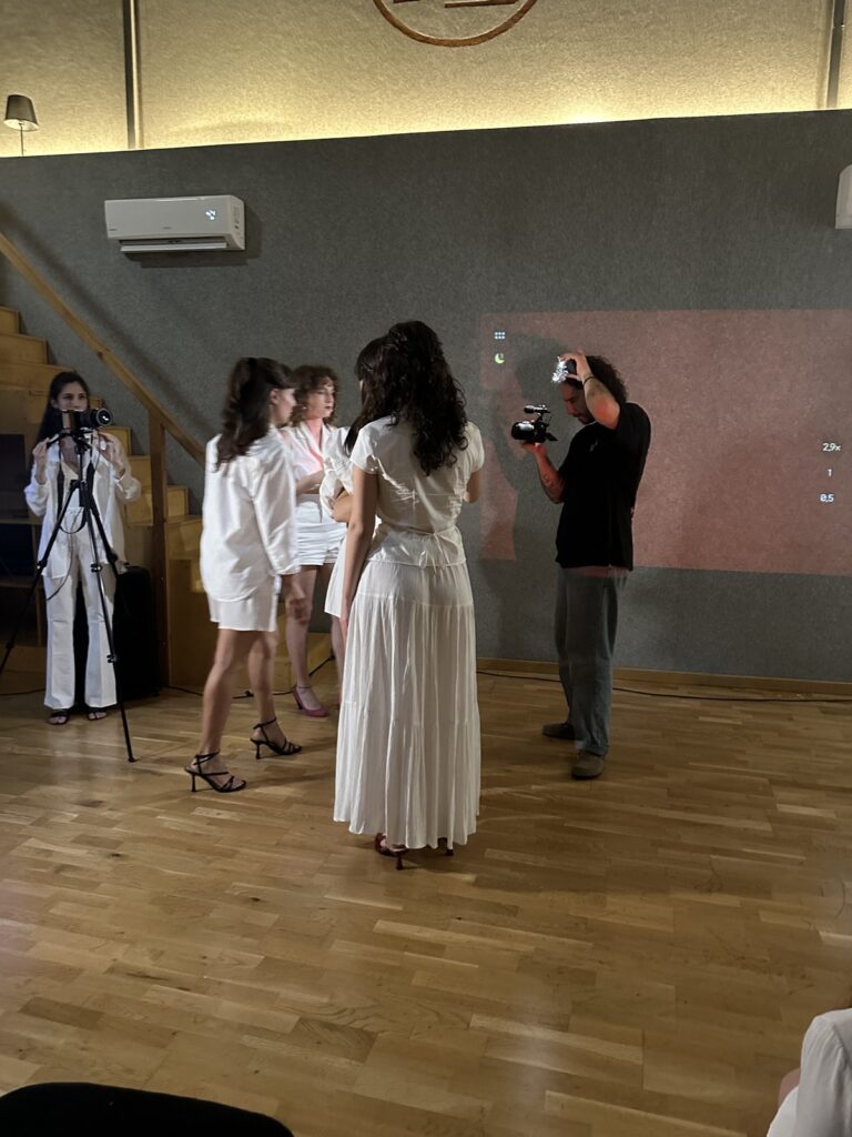 Persona: performer in bianco, cameraman e fonico in sala
