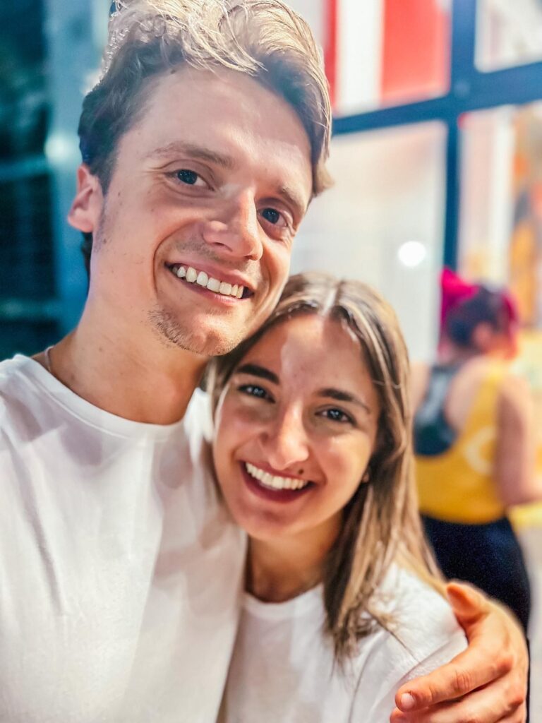 Two smiling students dressed in white, in a selfie