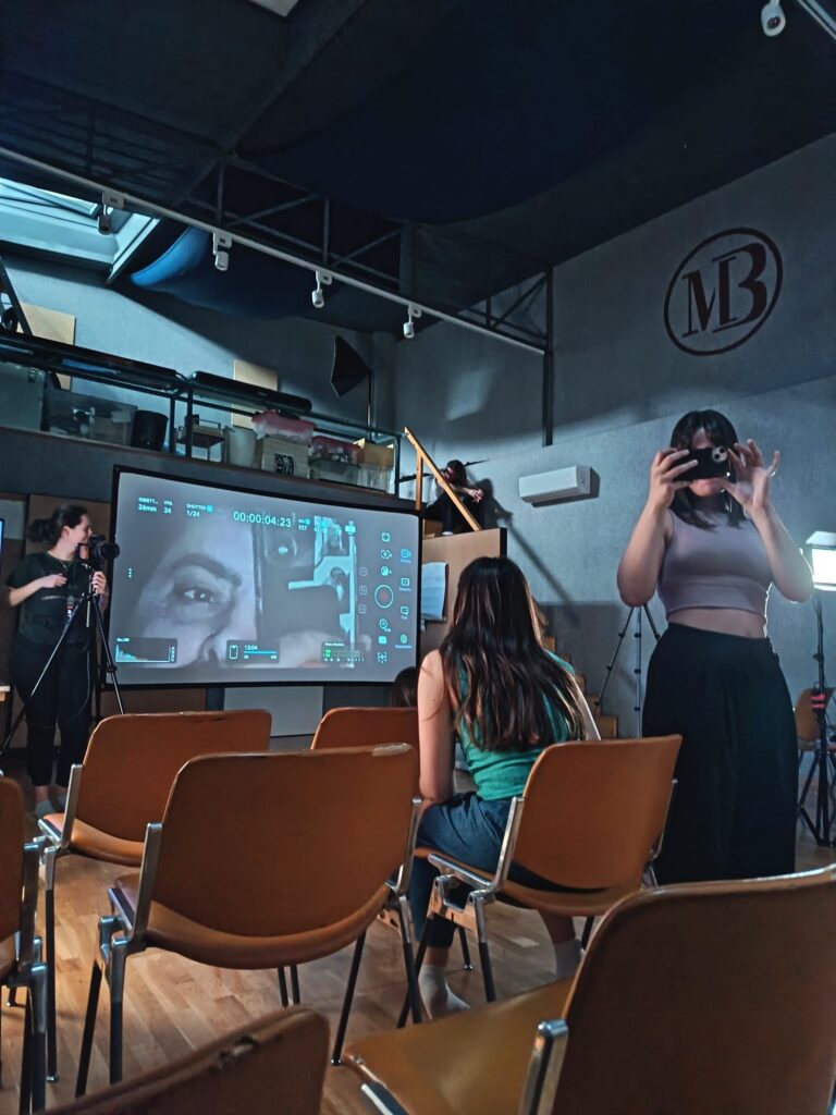 Studio with the MB logo, a monitor showing the camera frame and orange chairs