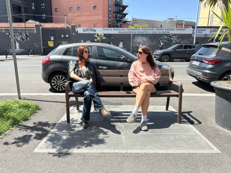 Two students sitting on the bench outside Mob Studios